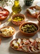 Spanische Tapas in kleinen Schälchen serviert mit Brot, Oliven, Schinken und Käse