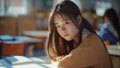 Asiatisches Mädchen mit traurigem Blick beim Lernen in der Schule