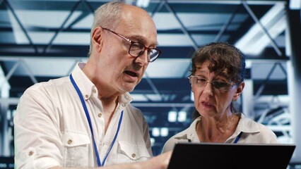 Poster - it programmers in data center using laptop to monitor energy efficient rackmounts. server cabinets u