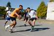 © Rob and Julia Campbell/Stocksy - A group of friends playing basketball together outside in the su