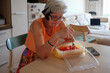 © Branislava Zivic Zrnic/Stocksy - Woman eating watermelon at home wile sitting on the table