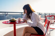 © Branislava Zivic Zrnic/Stocksy - A woman texting on her mobile on the terrace of a cruise ship