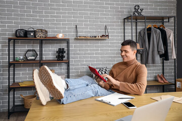 Wall Mural - Male online store seller writing on clipboard at table in warehouse