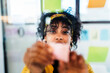 © Studio Marmellata/Stocksy - Female executive with sticky notes in creative workspace