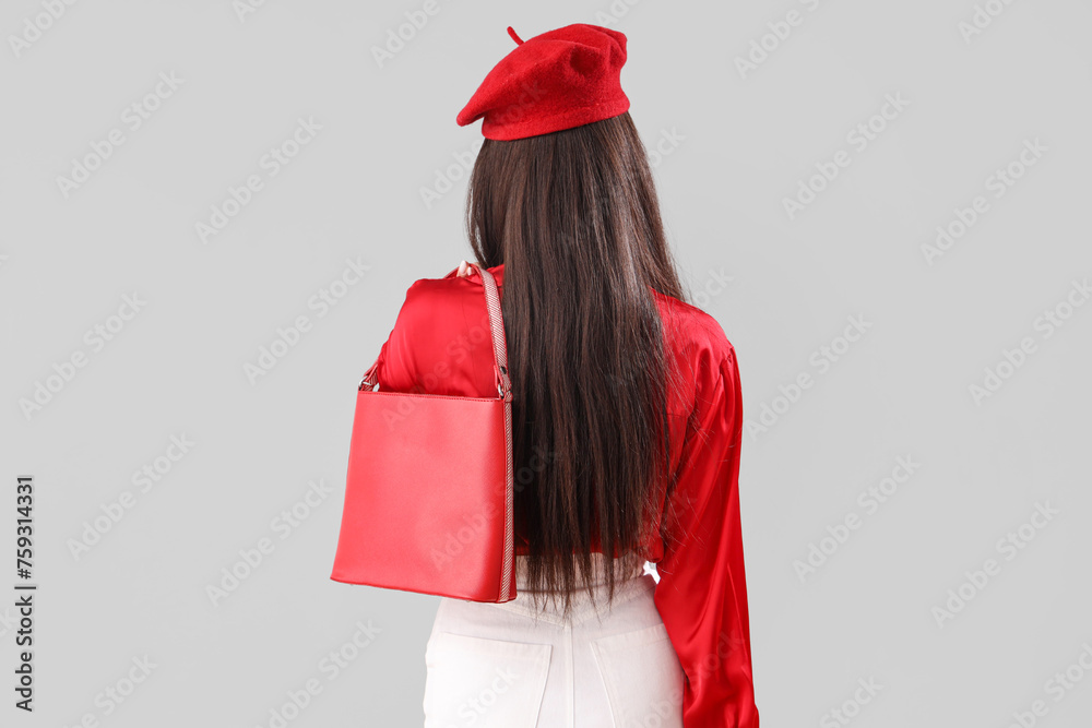 Beautiful young woman with stylish bag on grey background, back view