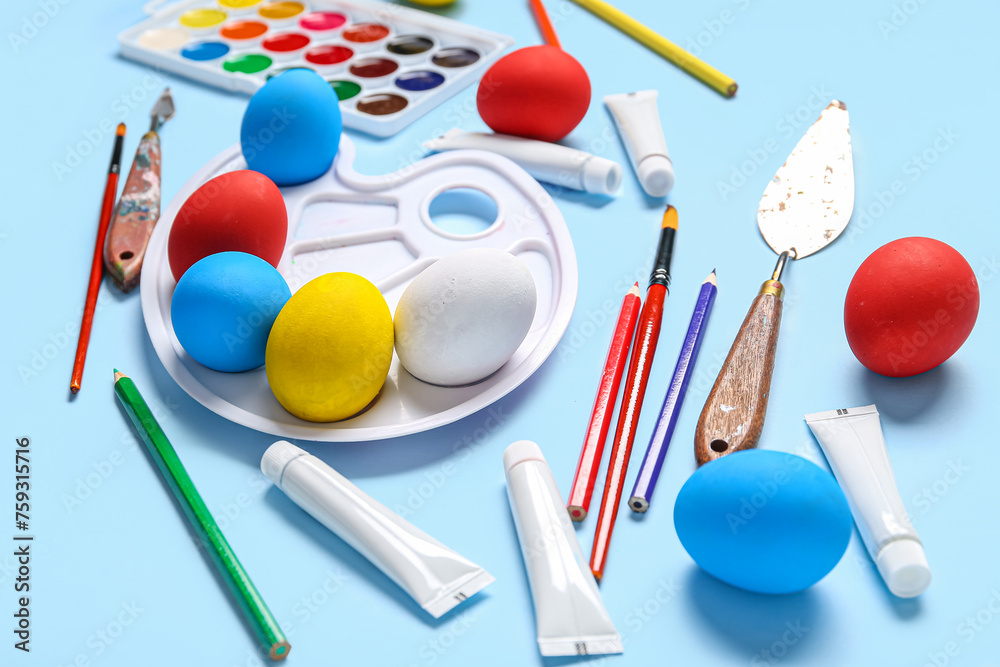 Composition with Easter eggs, pencils and paint palette on color background. Easter concept.