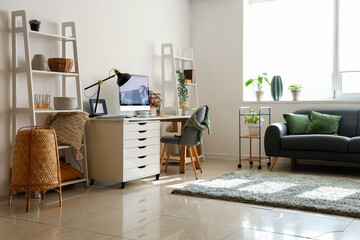 Interior of modern office with stylish workplace, sofa and shelving units