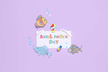 Sticker - Festive postcard for April Fools Day with clown and paper fishes on lilac background