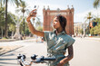 © Igor Kardasov/Stocksy - Stylish black woman taking selfie on smartphone on street