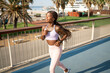 © Igor Kardasov/Stocksy - Happy black woman in sportswear jogging on walkway