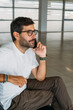 © Ivona Zivulj/Stocksy - Portrait of Handsome Man Sitting at Airport and Talking on  Phon