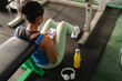 © Studio Marmellata/Stocksy - Young sportswoman using smartphone during break in gym