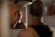 © Malquerida Studio/Stocksy - Cancer survivor woman looking in the mirror