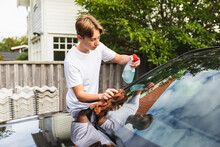 Teen Cleaning Vehicle From Dirt Outdoors