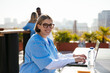 © BONNINSTUDIO/Stocksy - Medical assistant working on laptop on hospital terrace