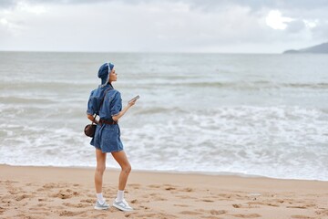 Wall Mural - Beach Bliss: Young Woman Walking Alone on Sandy Coastline, Enjoying the Sunset in Stylish Hat