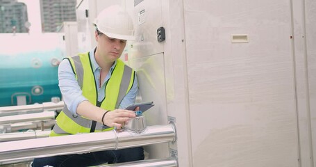 Canvas Print - Engineer inspecting insulated pipelines at an industrial site with a digital tablet.