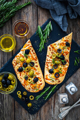 Wall Mural - Focaccia alle olive - baked sandwich with green and black olives and rosemary on wooden background
