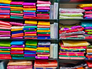 Wall Mural - Neatly stacked colorful designer silk saris in racks in a textile shop. Incredible India.