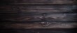 A closeup of a dark brown hardwood surface with a blurred background, showcasing the wood plank pattern in a rectangle shape. The darkness highlights the richness of the wood stain on the flooring