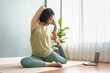 Asian Chinese woman doing fitness exercises on yoga mat at home. Healthy lifestyle, online yoga class on laptop concept.