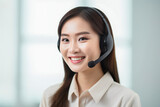Fototapeta Sypialnia - Asian smiling customer service assistant working in office. Handsome female helpline worker using computer in call centre office. VOIP Helpdesk headset.