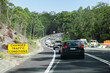 © Austockphoto - Changed traffic conditions sign and long line of cars backed up at roadwork site on highway