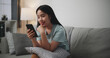 Selective focus, Happy young woman sitting on sofa enjoy using mobile phone for online shopping cashless in living room at home