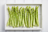Fototapeta  - White wooden tray with fresh green asparagus