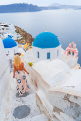 Wall Mural - woman model is walking strrets of Oia town on Santorini island in Greece. Travel mediterranean aegean of traditional cycladic Santorini white houses and blue dome