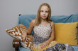 © millaf - Attractive kid girl relaxing on the sofa at home. Smiling girl enjoying day off sitting on the couch