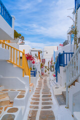 Wall Mural - narrow side street with traditional whitewashed walls and blue accents in Mykanos Greece. traditional windmill on the sea shore and colorful restaurants