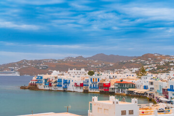 Wall Mural - narrow side street with traditional whitewashed walls and blue accents in Mykanos Greece. traditional windmill on the sea shore and colorful restaurants