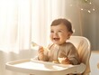 A baby smiling at the table, grabbing food with a spoon from a bowl
