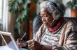 Elderly african american  woman freelancer  with headphone, hands holding stylus pen and working on digital tablet pc at home.  Portrait of senior woman writing making notes on tablet computer 