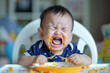 Little baby boy crying and screaming during eating, angry baby boy doesn't want to eat