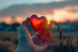 Heart shaped object in hand and sunset