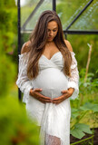 Fototapeta Sawanna - Serene Pregnant Woman Embracing Her Belly in Nature
