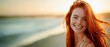 A beautiful red haired woman smiling at the camera,  on a beach, summer, travel and vacation concept, horizontal background, copy space for text