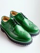 Pair of green leather brogue shoes on white background.