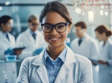  Latina Woman Researcher In A White Lab Coat And Glasses Working In A Modern Biomedical Laboratory.