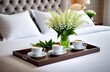 Tray with cups of coffee drink, vase with lily of the valley flowers on the bed in the bedroom