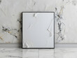 A grey rectangle art frame on a marble wall made of natural material