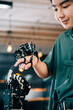 © sorapop - Teenage boy in a technical college learns technology testing a robot hand and arm touching fingers for educational skill growth. Embracing futuristic AI and humanity.