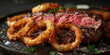 Juicy steak and crispy onion rings served on a sleek black plate with a side of salt and pepper seasoning