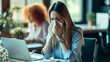 © MP Studio - woman in a blue shirt sitting at a desk, blowing her nose into a tissue with a laptop in front of her