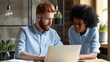 © MP Studio - professional man and woman discussing work while looking at a laptop screen together in an office setting