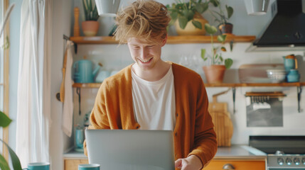 Sticker - A man in an orange cardigan and white shirt is laughing while using a laptop and holding a blue mug at a kitchen table surrounded by houseplants.