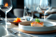 Pristine pan-seared salmon on a bed of greens served in a stylish restaurant with wine glasses