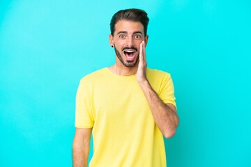 Young caucasian man isolated on blue background with surprise and shocked facial expression